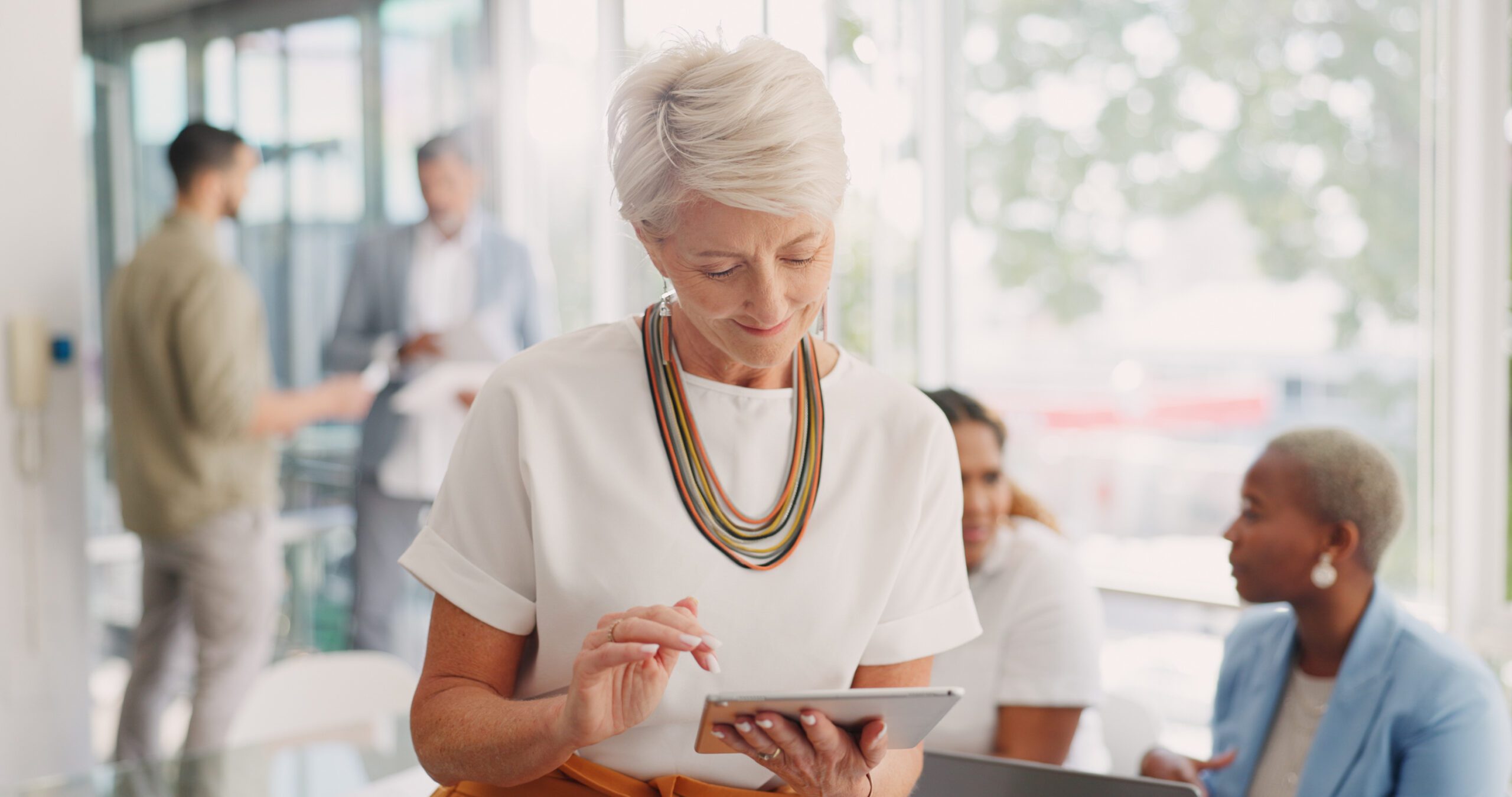 Business woman, senior and digital tablet for leader planning, thinking and research while in business meeting. Mature woman, internet and search while leading a meeting with creative group in office.